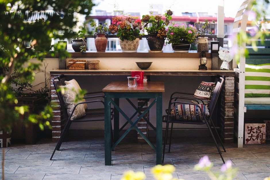 Knusse stadsbalkonruimte met bloemen en houten vloer.